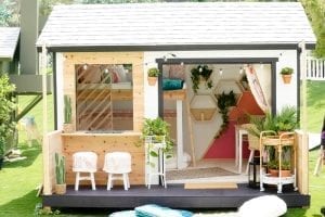 White shed with black patio. Doors have been removed to reveal colorful interior.