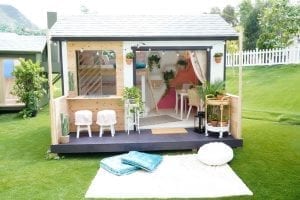 White shed with black patio. Doors have been removed to reveal colorful interior.
