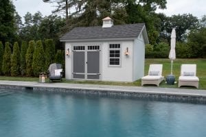 Pool shed next to in-ground pool and chairs.