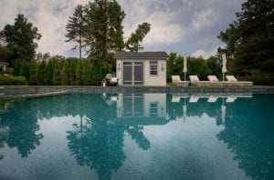 Pool shed wide shot with four poolside chairs.