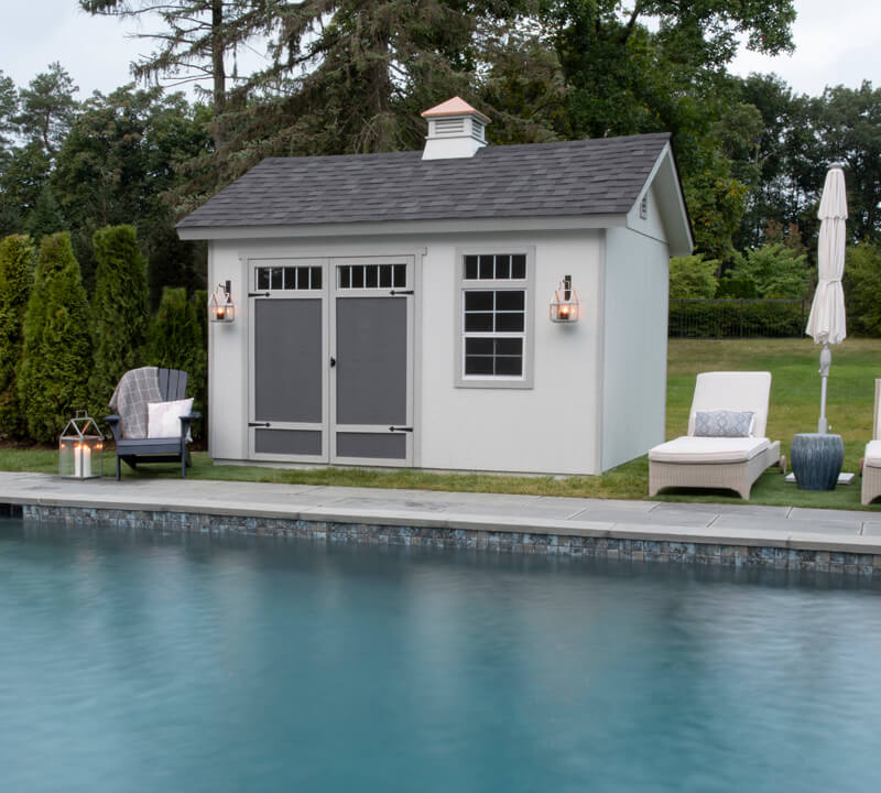Pool shed next to in-ground pool and chairs.