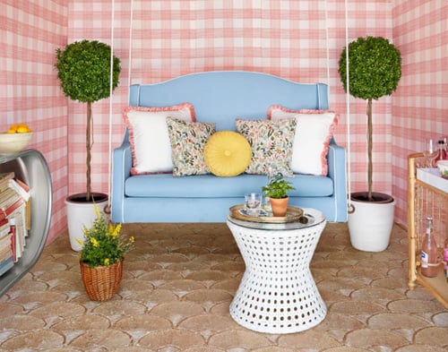 Bar She Shed: Blue hanging chair with decorative pillows, round coffee table, and bar cart.
