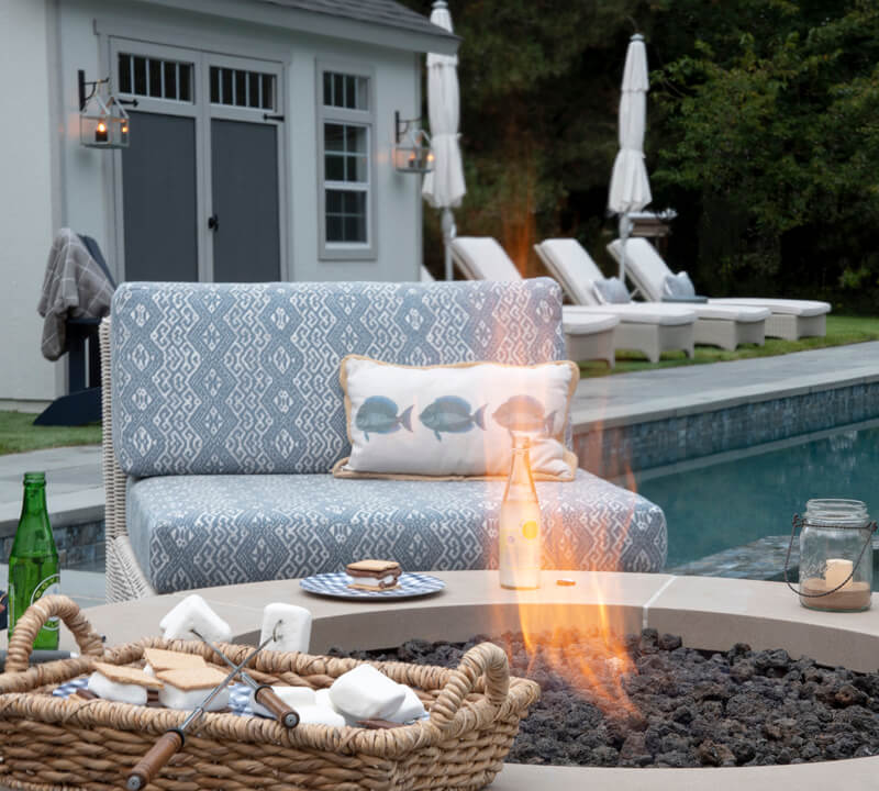 Pool shed with fire pit and chair in foreground.