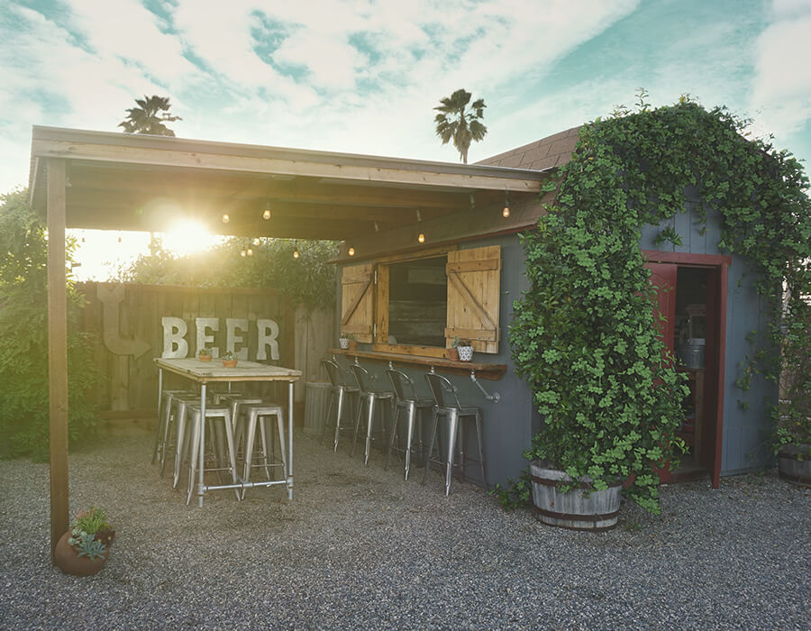 Office and bar shed: Exterior of blue shed. Window opens up to shelf table and four chairs. Awning extends from shed. Table and six bar stools under awning.