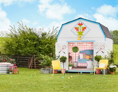 Game room She Shed: Barn style shed shown with doors open revealing colorful interior. Tennis rackets hung on doors, croquet setup outside.