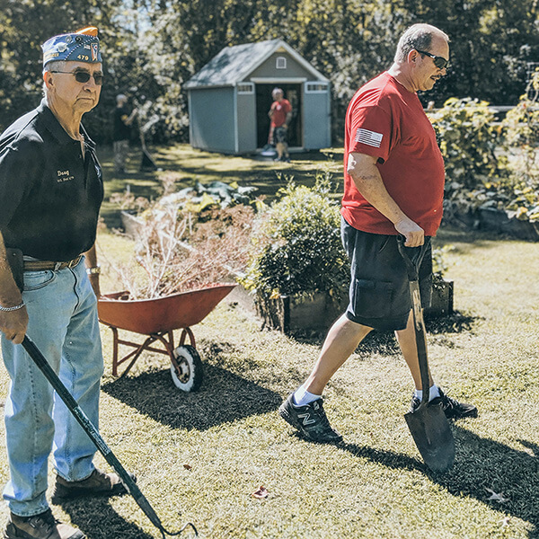 Image of veterans using wheelbarrows for gardening veterans shed gardening