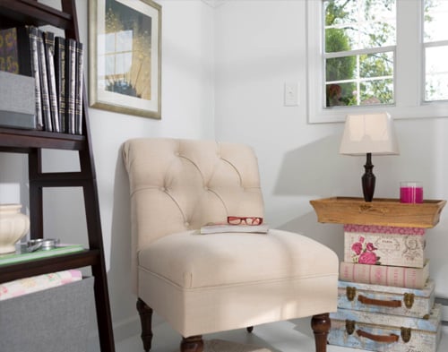 She Shed reading nook with chair and side table next to window.